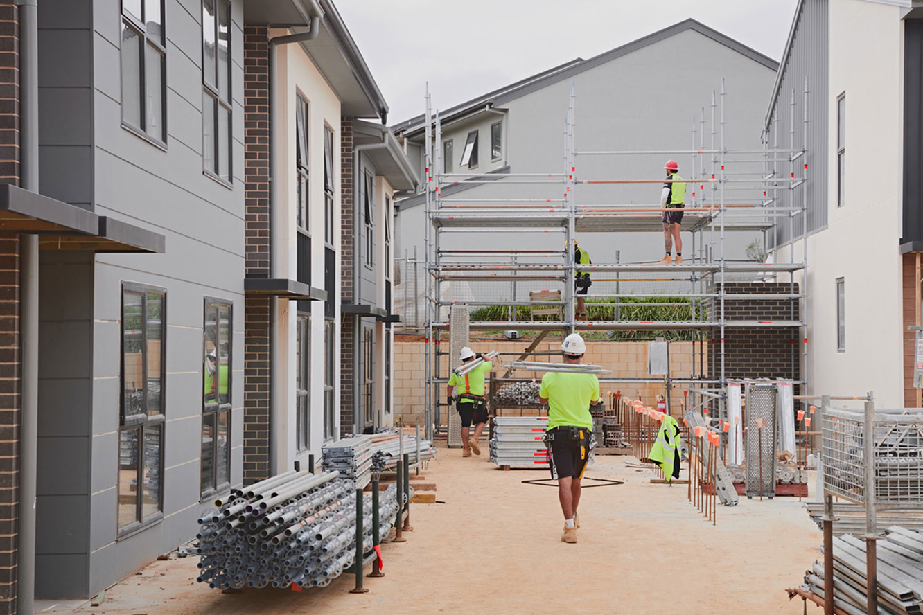 Workers assembling scaffolding at townhouse development site