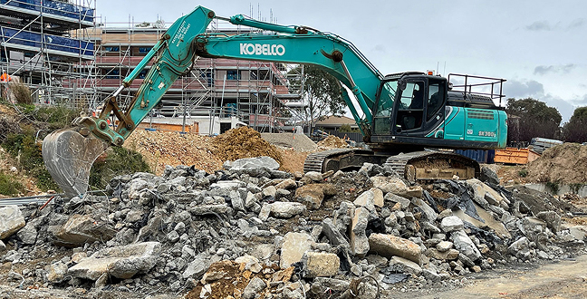 Excavator clearing rubble at the Ives construction site
