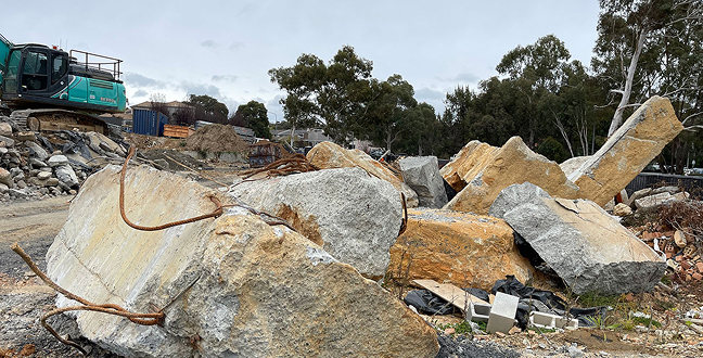 Heavy machinery working among large rocks at Ives development site