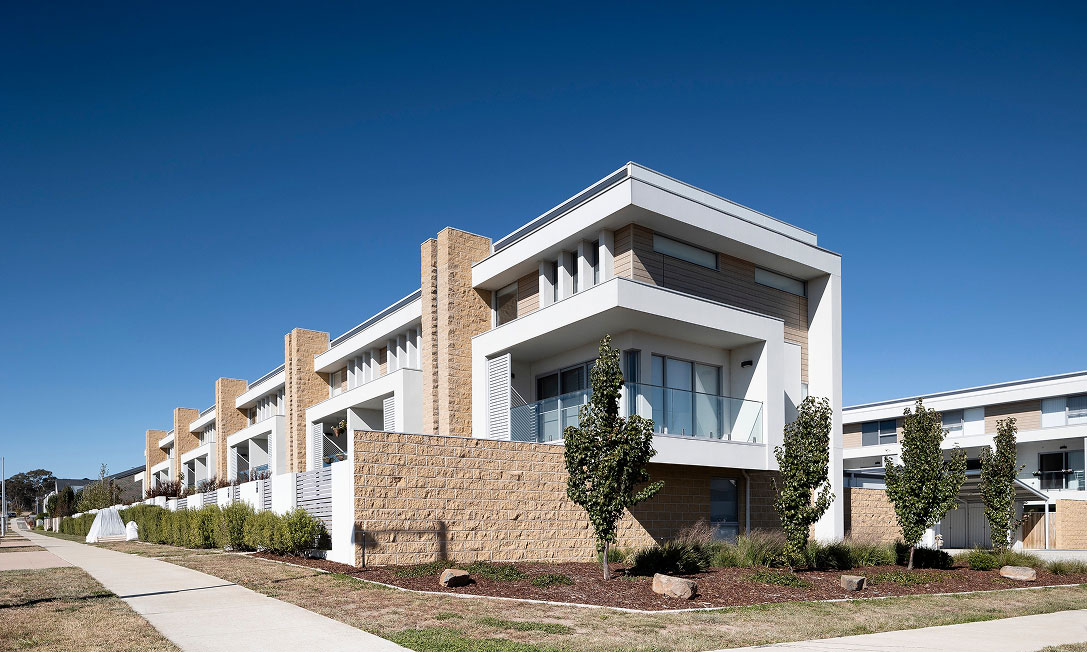Nest II townhouses in Lawson, Canberra with blue-grey skillion roofs, earthy brickwork and black-framed glazing